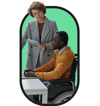 A woman in a wheelchair is engaged in inclusive employment by talking to a man at a desk.