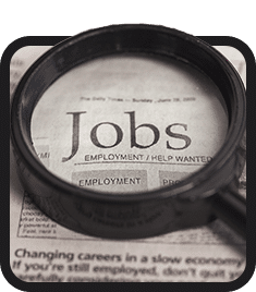 A magnifying glass over a newspaper with the word jobs, highlighting inclusive employment opportunities.