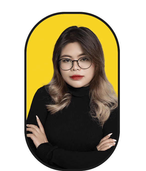A woman with glasses looking for work posing in front of a yellow background.